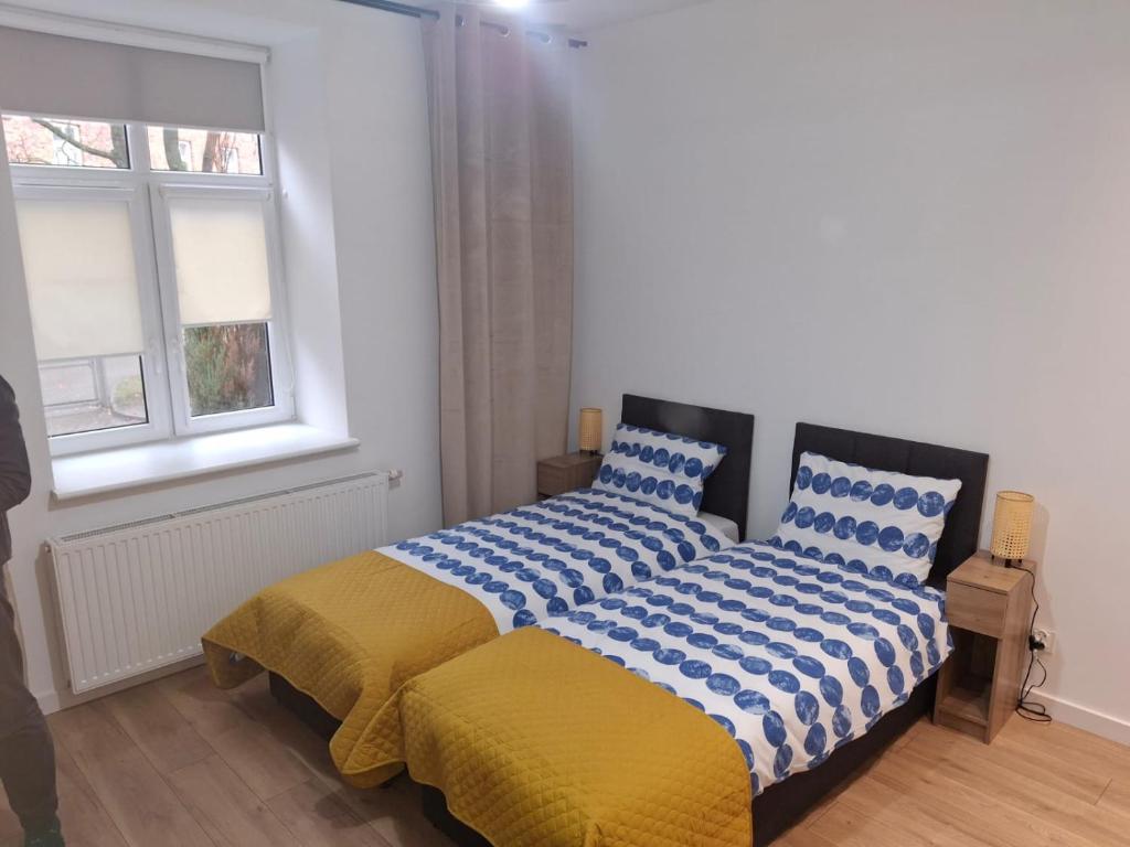a bedroom with a bed with blue and yellow sheets at Studio przy Szpitalu in Szczecin