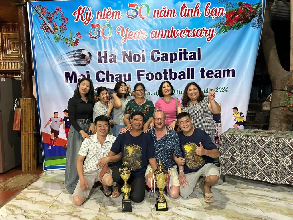 eine Gruppe von Menschen posiert für ein Foto vor einem Banner in der Unterkunft An' Home Mai Chau in Mai Châu