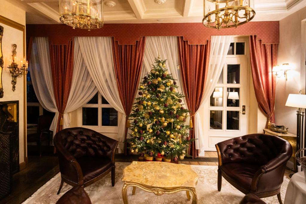 a christmas tree in a living room with two chairs at Imperial Hotel & Restaurant in Vilnius