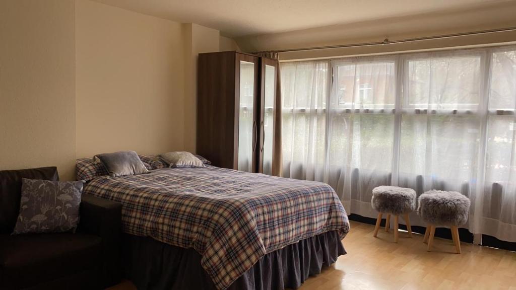 1 dormitorio con 1 cama con manta a cuadros y ventana en 37chats studio, en Londres