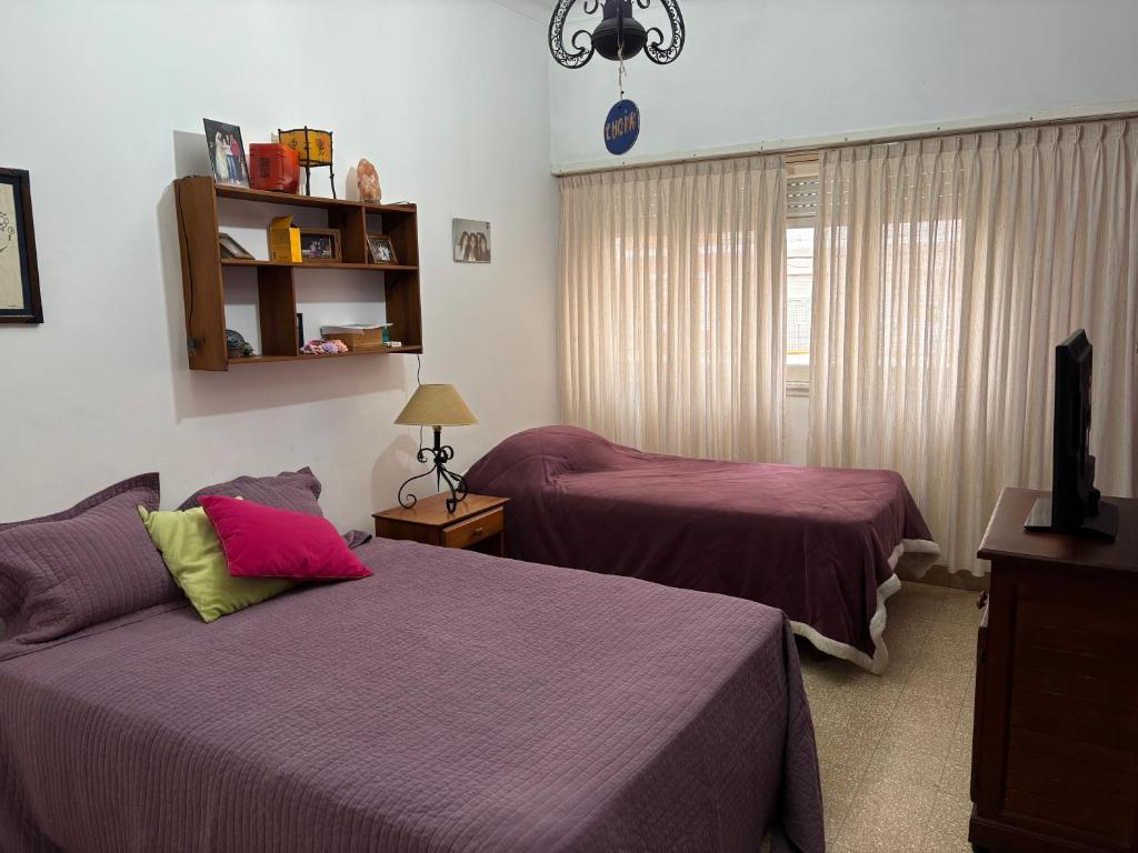 a bedroom with two beds with purple sheets and a window at Amplio departamento 4 ambientes miramar in Miramar