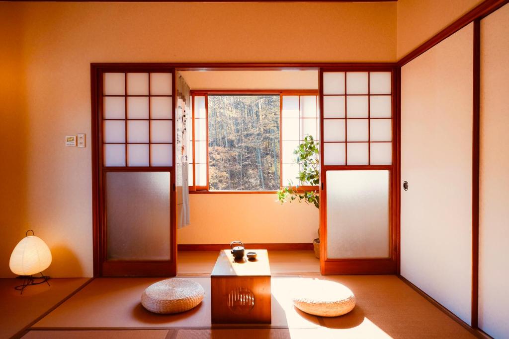 ein Raum mit zwei Türen und einem Tisch und einem Fenster in der Unterkunft KeiCo 定員12名 駐車場12台 露天風4分 河口湖6分 富士急10分 ふじてんスノーリゾート10分 in Narusawa