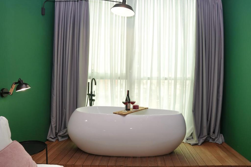 地拉那Ambassador Skyline Apartments的窗户前带白色浴缸的浴室