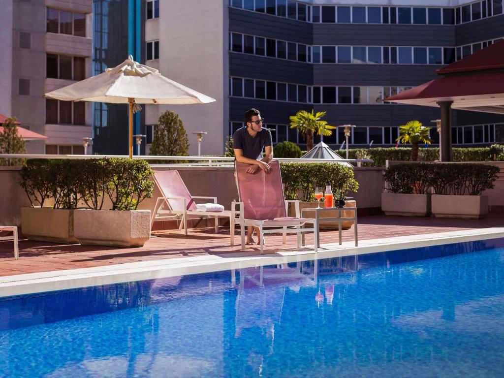 Ein Mann steht neben einem Schwimmbad. in der Unterkunft Pullman Madrid Airport & Feria in Madrid