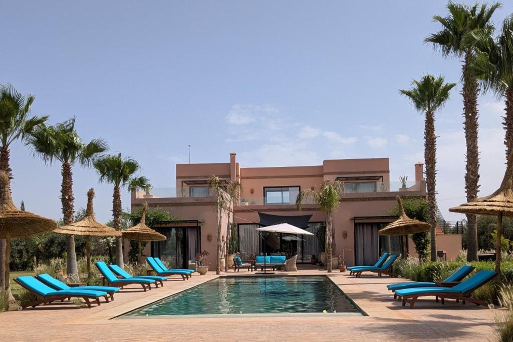 a resort with a pool and chairs and palm trees at Villa Sbaa Marrakech in Marrakesh