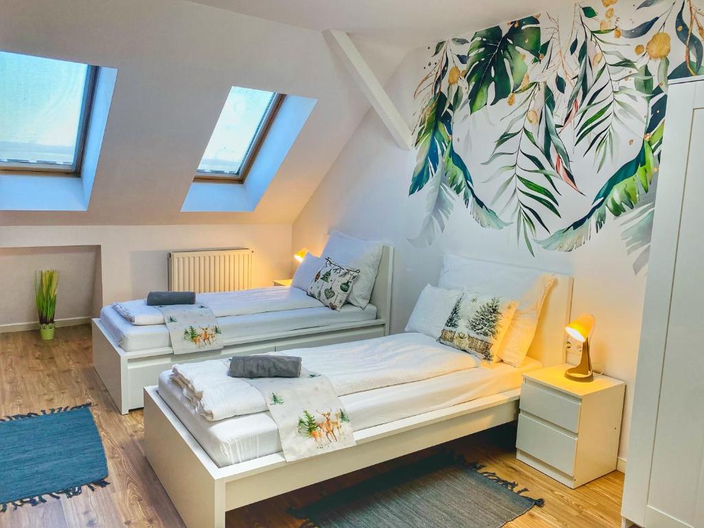 - une chambre mansardée avec 2 lits et des fenêtres dans l'établissement Magenta Apartman, à Mórahalom