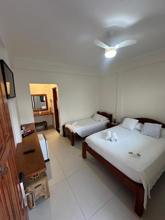 a hotel room with two beds and a mirror at Pousada Acqua Azul in Bertioga