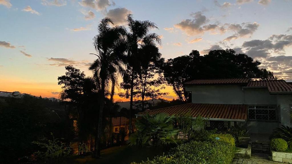 Una casa con una palmera frente a una puesta de sol en Chácara do Sossego, en Piracaia