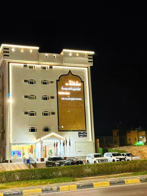 un grand bâtiment blanc avec des voitures garées devant dans l'établissement سفانة هلا للشقق المخدومة, à Hafr Al Baten
