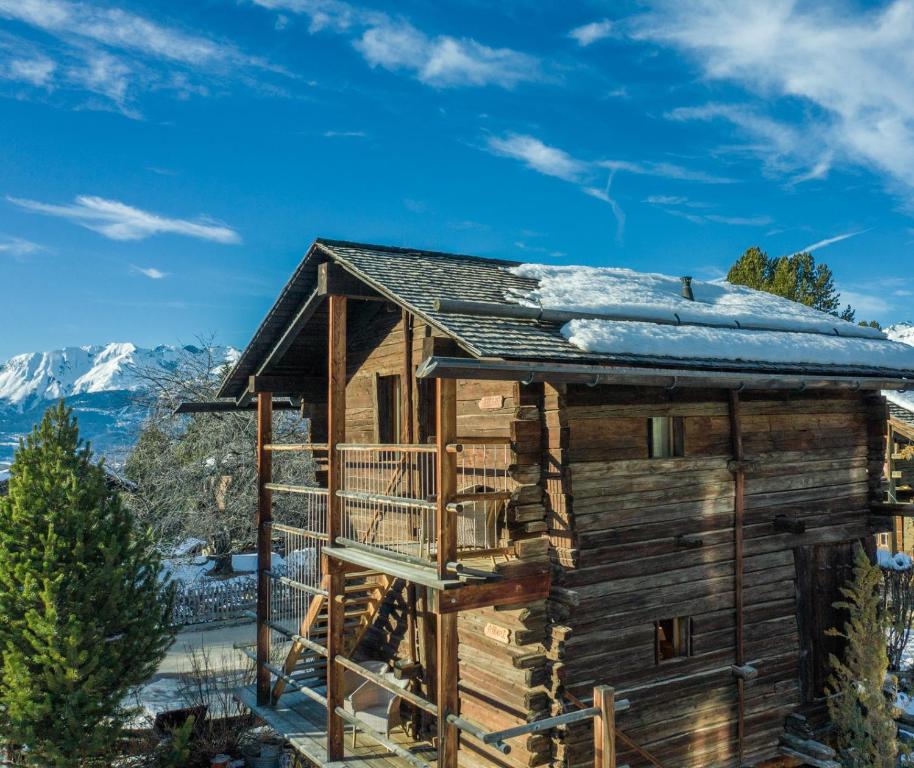 Cabaña de madera con techo cubierto de nieve en Les Mazots du Hameau des Biquettes - Charme Alpin et Cuisine équipée, en Vercorin