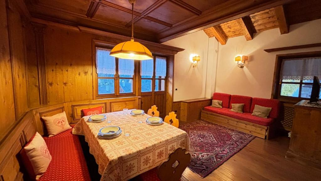 een eetkamer met een tafel en rode stoelen bij Mansarda Ca Geranei in San Vito di Cadore
