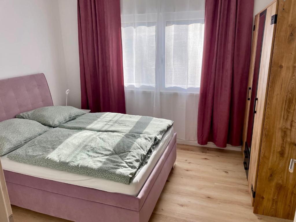 un letto in una camera da letto con tende viola e una finestra di Sunny Garden Bungalow a Besednice