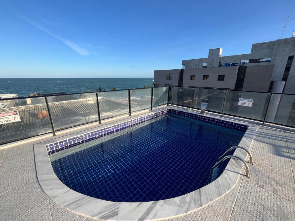 a swimming pool on top of a building next to the ocean at Ametista 2 Beira Mar in Maceió
