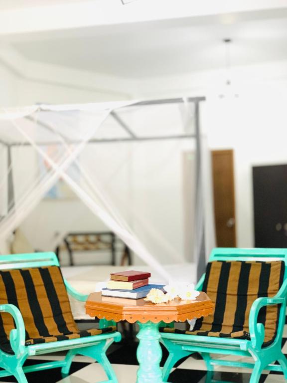 a table with books on it next to two chairs at Conch Villa- 3 Min walk to the beaches in Tangalle