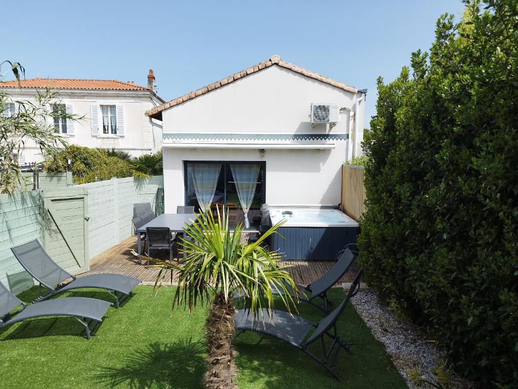 a backyard with chairs and a table and a house at La pointe du Chay in Angoulins-sur-Mer