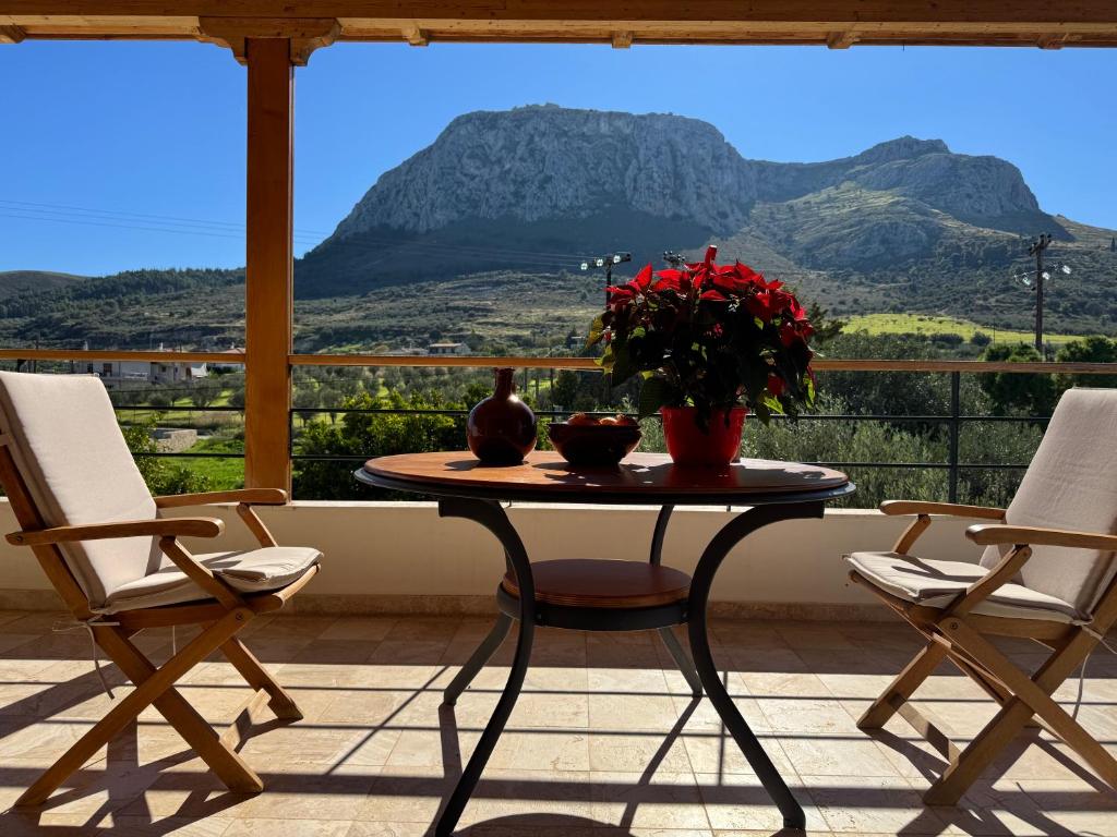 einen Tisch und Stühle auf einem Balkon mit Bergblick in der Unterkunft Double view apartment in Kórinthos