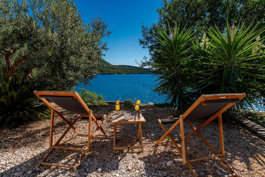 2 Stühle und ein Tisch neben einem See in der Unterkunft Silvio Beach House - Shoreline Haven in Mlini