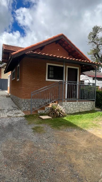 a small house with a porch and a balcony at Chalés Ipe Amarelo in Camanducaia