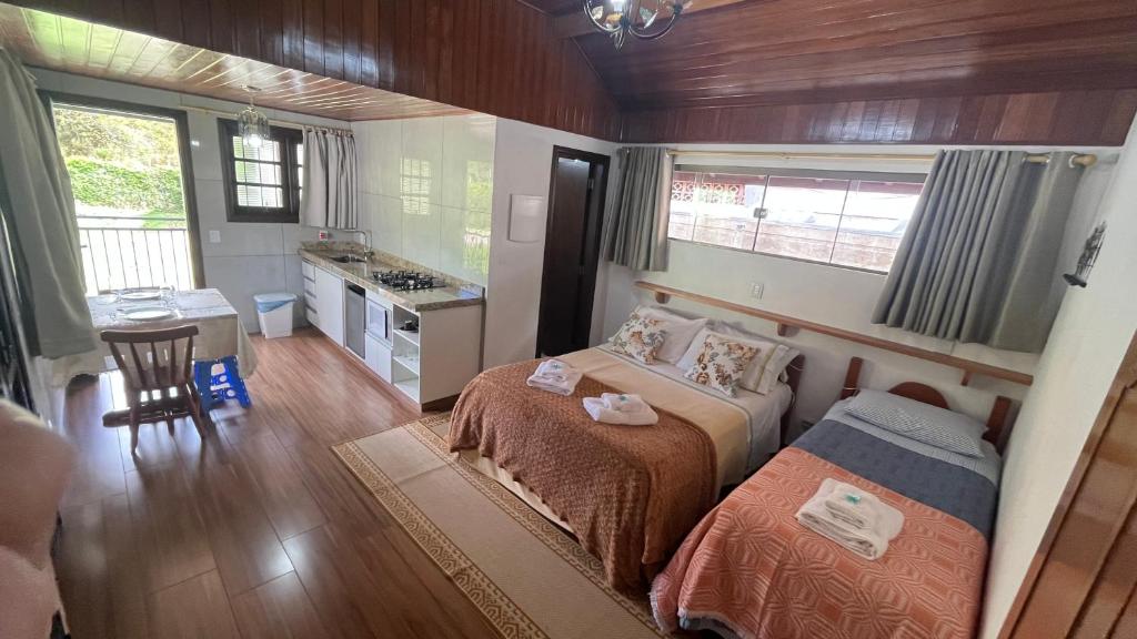 ein kleines Schlafzimmer mit einem Bett und einer Küche in der Unterkunft Chalés Ipe Amarelo in Camanducaia