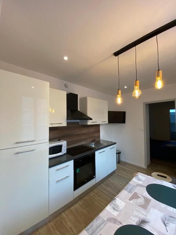 eine Küche mit weißen Schränken und einem Tisch in der Unterkunft Appartement calme à Saint Maixent l'Ecole in Saint-Maixent-lʼÉcole