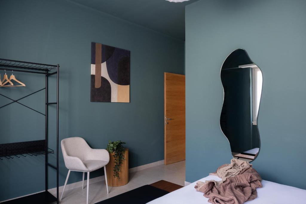 Cette chambre comprend un lit, une chaise et un miroir. dans l'établissement L'Atelier - 2 min walk to Bernina Express, à Tirano