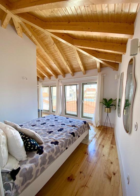 a bedroom with a bed in a room with wooden ceilings at VIVA - Rooftop Terrace View Flat in Porto