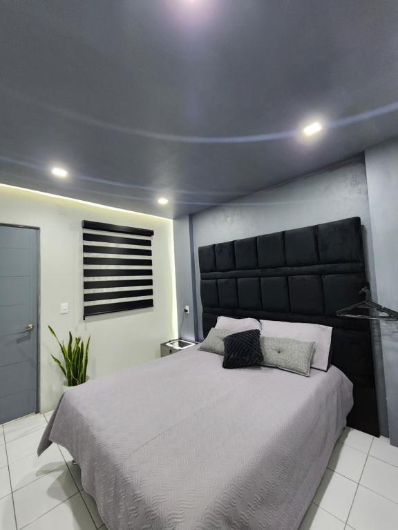 une chambre avec un grand lit avec une tête de lit noire dans l'établissement departamento Saturno, à Guadalajara