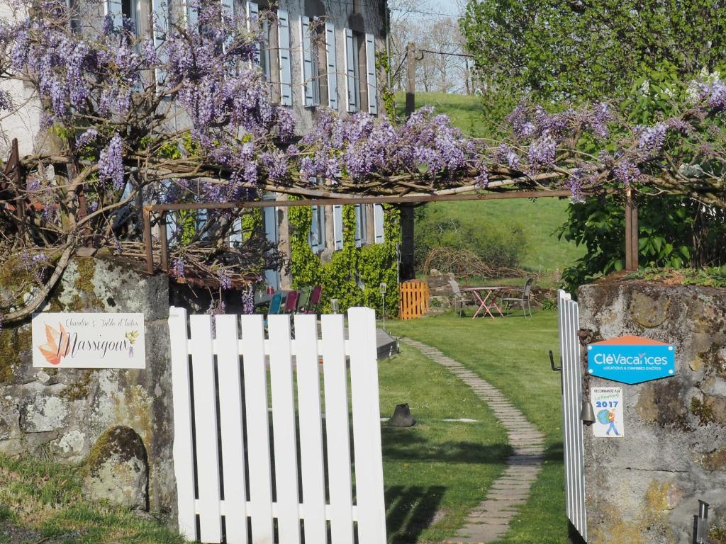 a white fence in front of a house with purple wisterias at Chambres d'hôtes de Massigoux in Aurillac