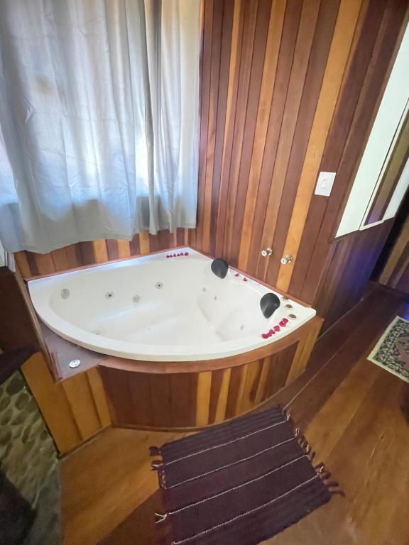 a jacuzzi tub in a room with wooden walls at Suítes cantinho de mauá in Visconde De Maua