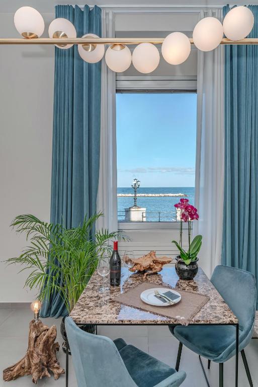 a dining room with a table and chairs and a large window at Alta Marea Apulia sea view in Bari
