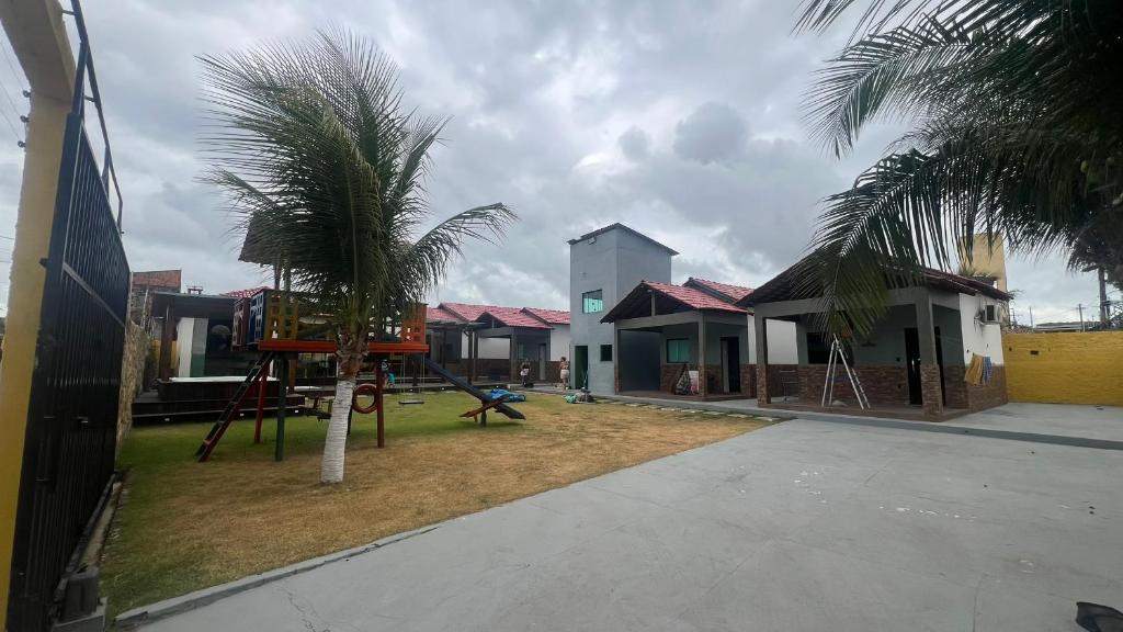 un parco giochi di fronte a una casa con palme di Chalés do Atlântico a Salinópolis