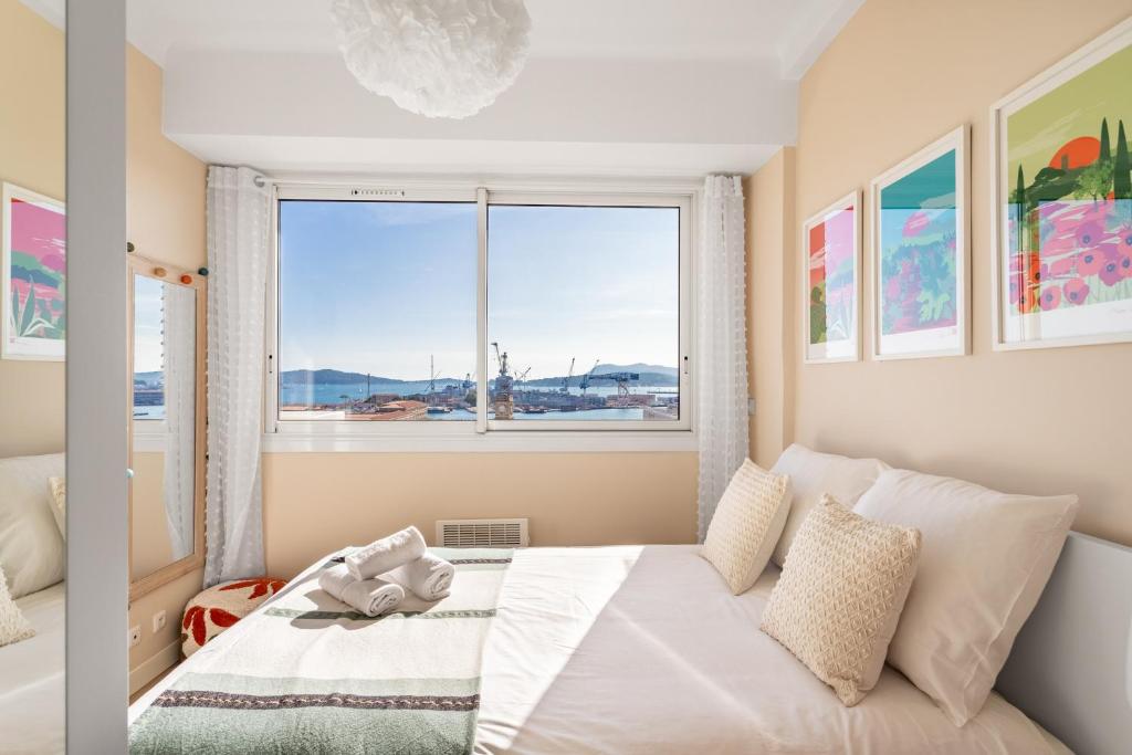 a bedroom with a bed and a large window at Magnifique appartement climatisé vue mer in Toulon