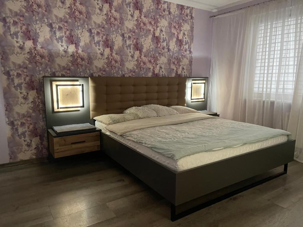 ein Schlafzimmer mit einem Bett und einer Wand mit Blumen in der Unterkunft Big apartment for four in Klaipėda