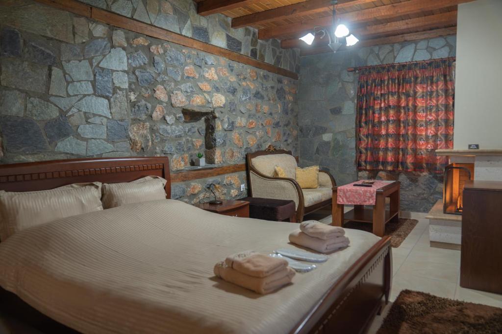 a bedroom with a bed and a stone wall at ΞΕΝΩΝΑΣ ΘΕΑ in Palaios Agios Athanasios