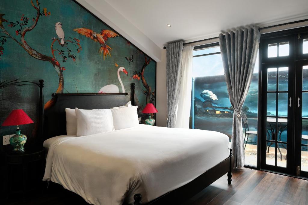Un dormitorio con una cama grande con pájaros en la pared. en Indochine Hotel Hoi An, en An Bàn (2)