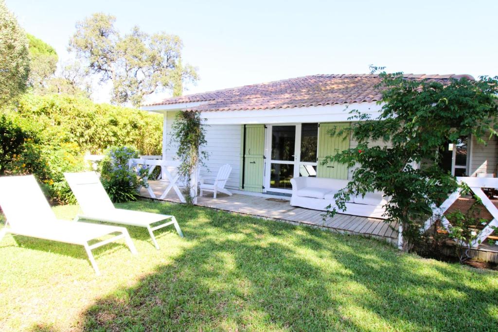 einen Hof mit weißen Stühlen und ein Haus in der Unterkunft GASMED29 - Golfe de St-Tropez - Maison climatisée 3 chambres avec beau jardin et aperçu mer in Gassin