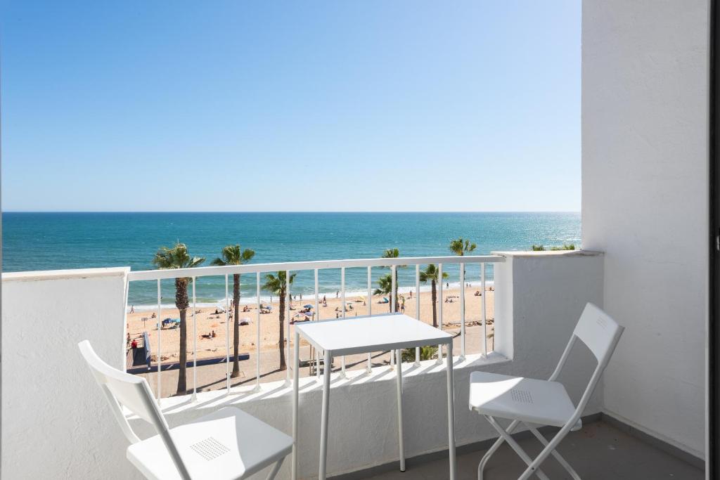 ein Balkon mit Tisch und Stühlen und der Strand in der Unterkunft Maresia - Front beach - Quarteira in Vilamoura