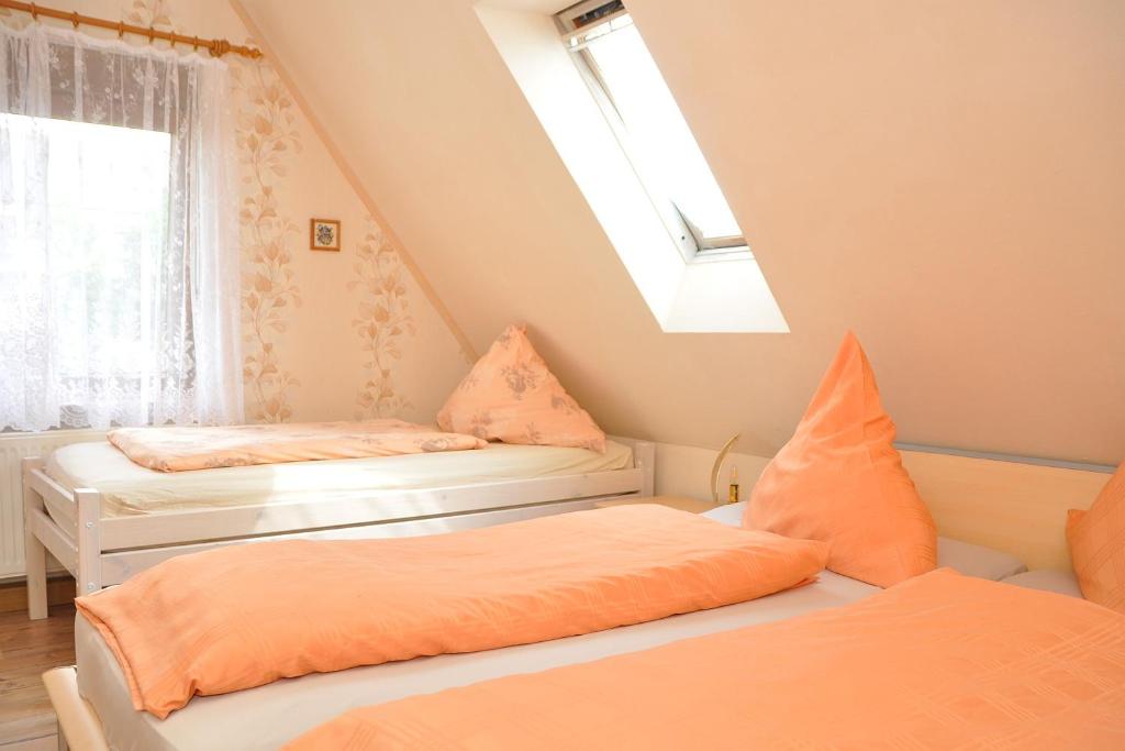 2 Betten mit orangefarbener Bettwäsche in einem Zimmer mit Fenster in der Unterkunft Ferienwohnung Neubert in Wolkenstein