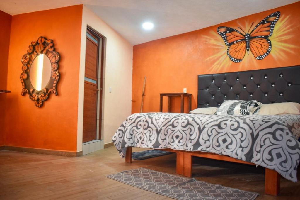 - une chambre dotée d'un lit avec un papillon sur le mur dans l'établissement Departamento céntrico con terraza, à Mineral de Angangueo