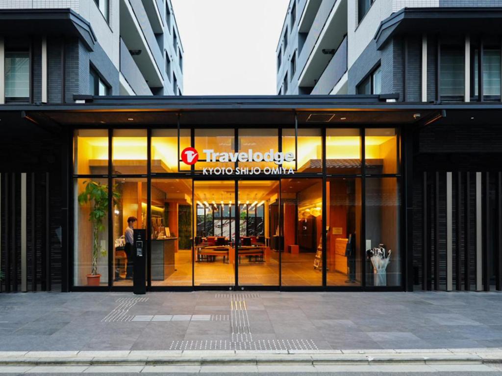Un gran edificio de cristal con un hombre de pie en el exterior en Travelodge Kyoto Shijo Omiya, en Kioto