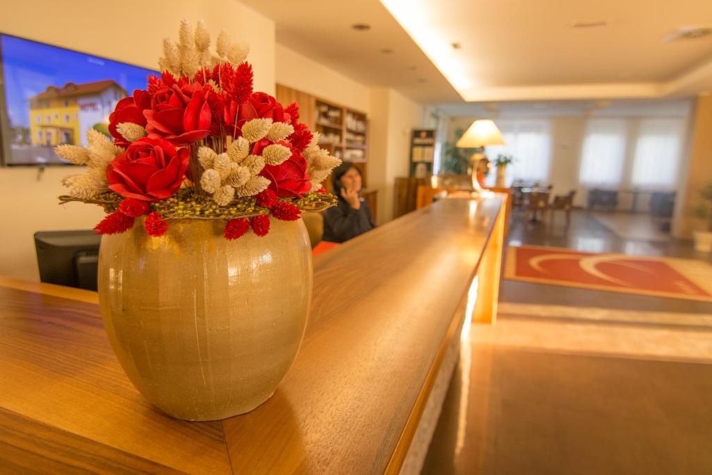 Un jarrón con flores rojas sobre una mesa. en B&B Bau, en Maribor