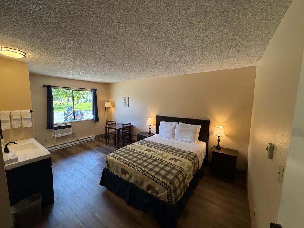 ein Schlafzimmer mit einem Bett und einem Tisch und einem Fenster in der Unterkunft Winthrop Inn in Winthrop