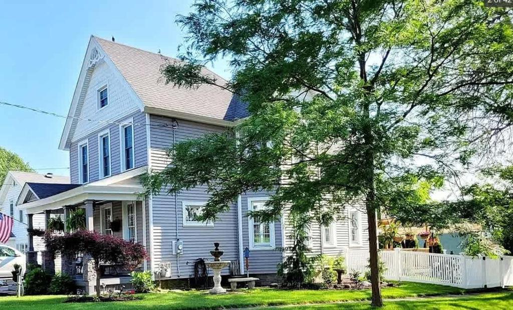 a white house with a tree in front of it at The Hamilton Harbor House in Oswego