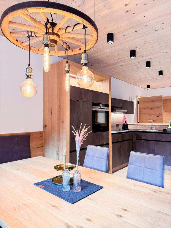 a dining room table with blue chairs and a large chandelier at Haus Fontanas by Emju - Vandans in Vandans