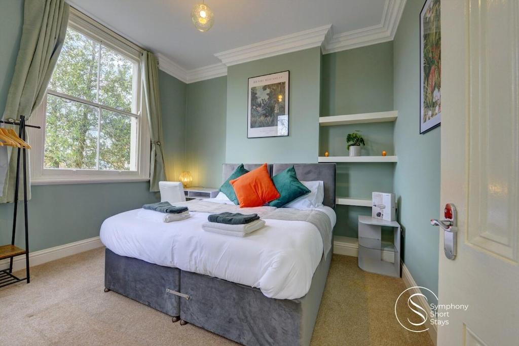 ein Schlafzimmer mit einem großen Bett mit bunten Kissen in der Unterkunft Leamington Spa Warwick Place Apartments in Leamington Spa