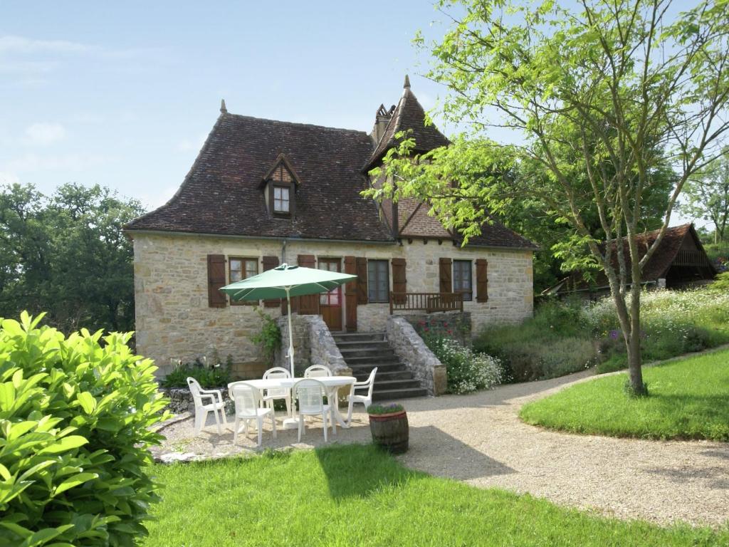 a house with a table and chairs and an umbrella at Padirac Countryside Charm in Padirac