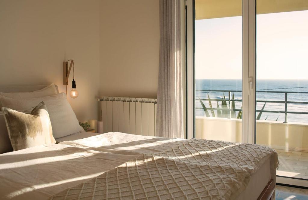 een slaapkamer met een bed met uitzicht op de oceaan bij Panorama SeaView House in Marinha Grande