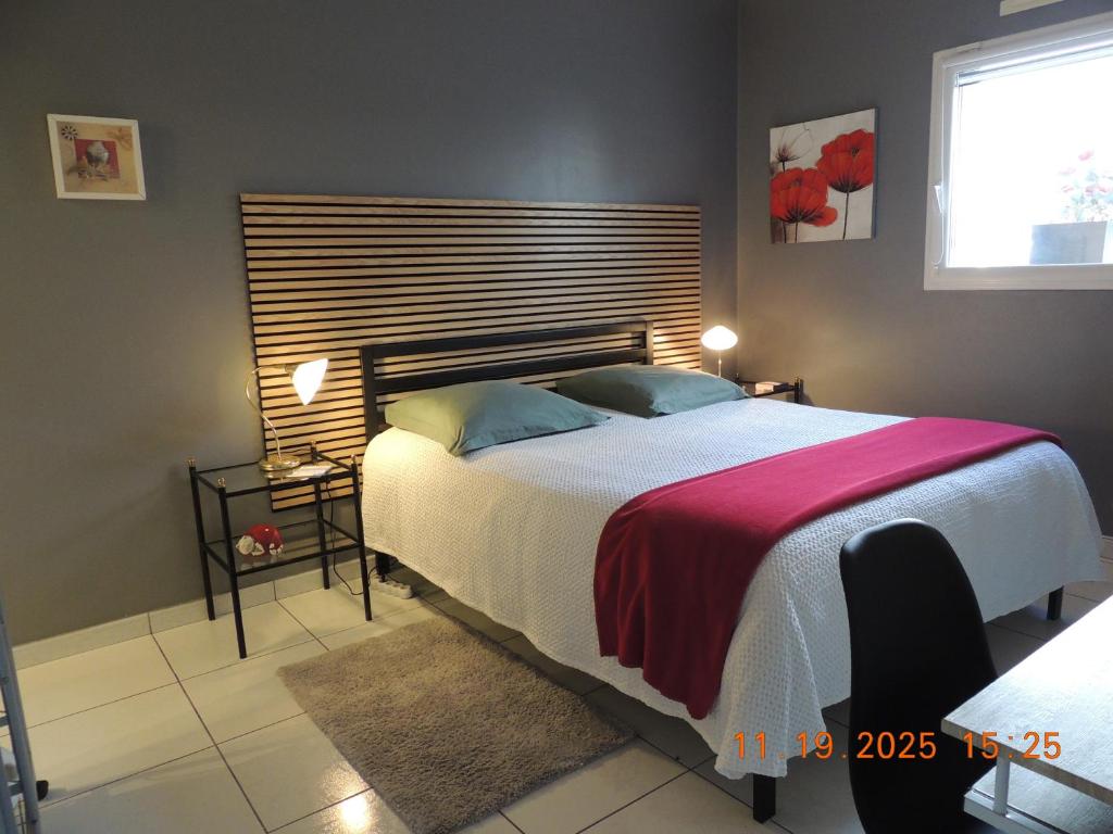 a bedroom with a large bed with a wooden headboard at Les Coquelicots Chambre d' hote avec grand lit et salle d'eau privative pour une persone ou un couple in Vern-sur-Seiche