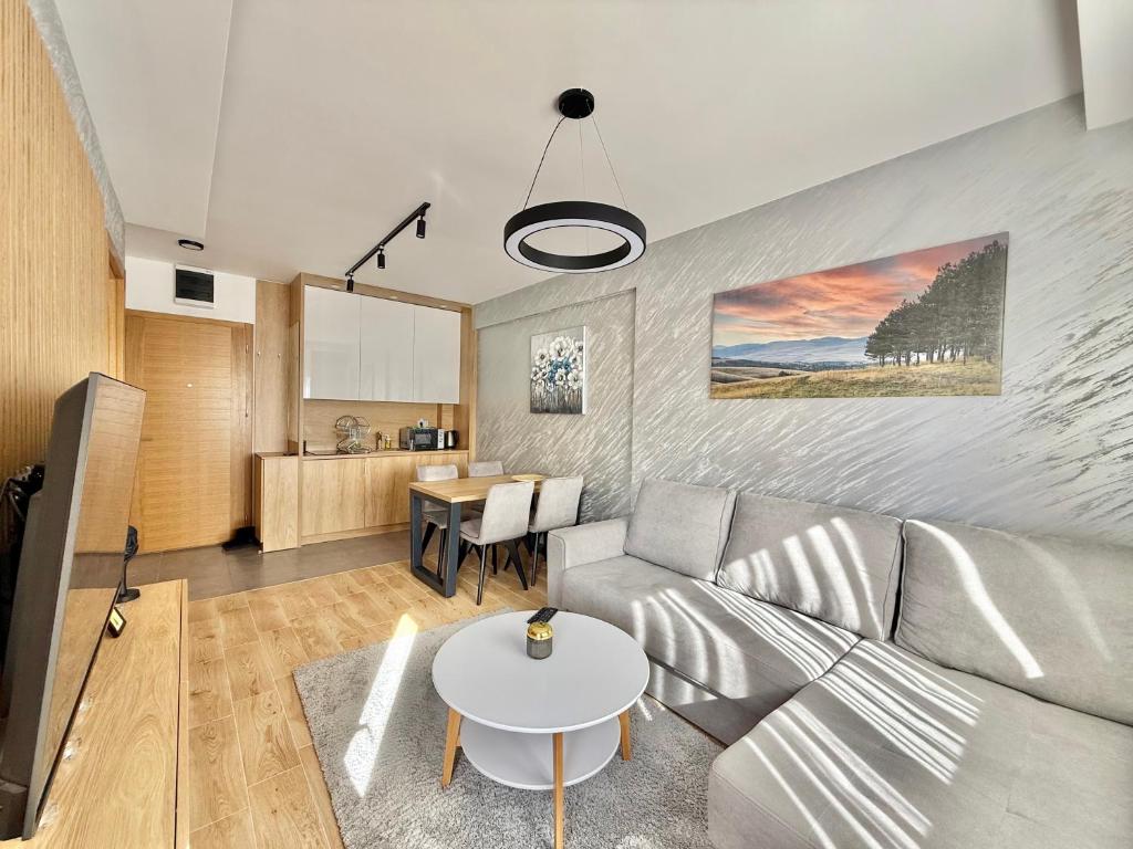 uma sala de estar com um sofá e uma mesa em Zlatibor Prestige Apartman 18 em Zlatibor