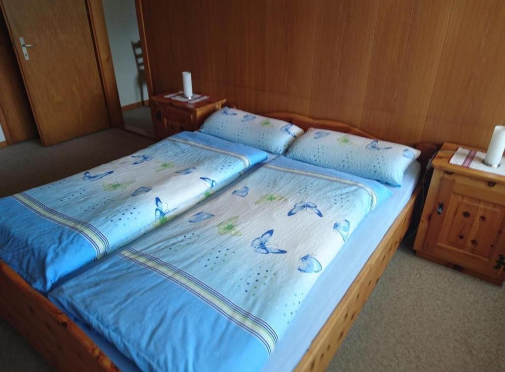 a bed with a blue comforter and pillows on it at Obererli in Hasliberg